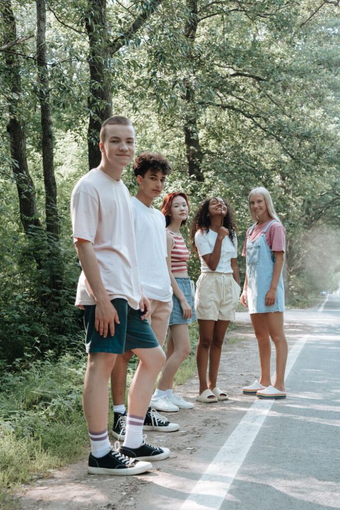 pexels photo 10484479 Diverse group of teens relaxing by a forest road, enjoying a sunny summer day.