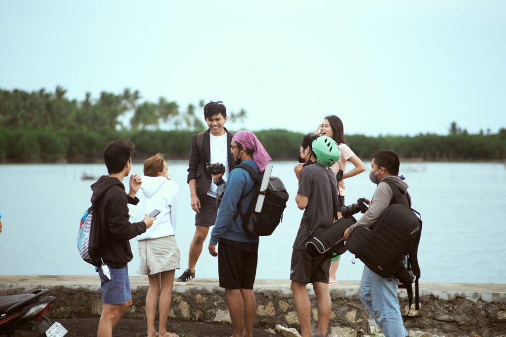 pexels photo 10756911 10756911 A group of young adults laughing and hanging out by a serene lakeside.