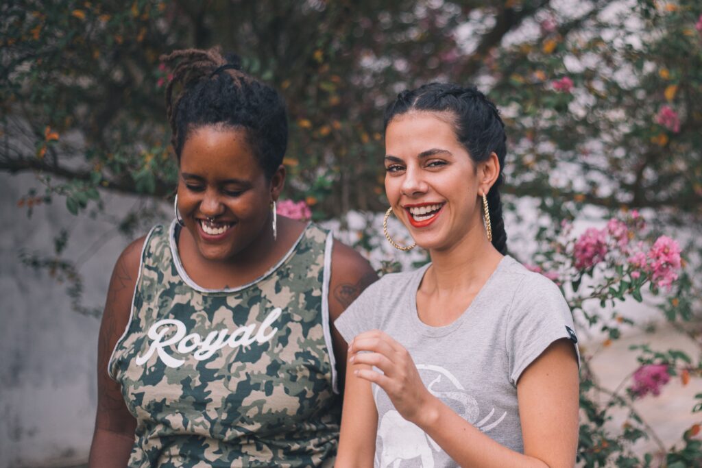 pexels photo 1772474 1772474 Two women smiling and laughing outdoors surrounded by nature, conveying happiness and friendship.