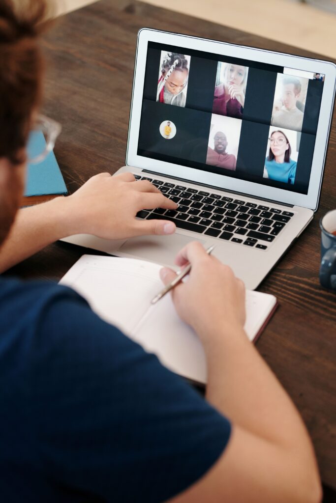 pexels photo 6147014 6147014 Person taking notes during a virtual meeting on a laptop screen with a diverse team.