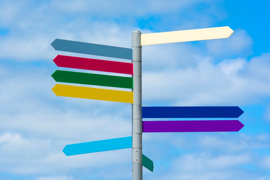 Home Multicolored directional signpost against a vibrant blue sky, offering guidance.