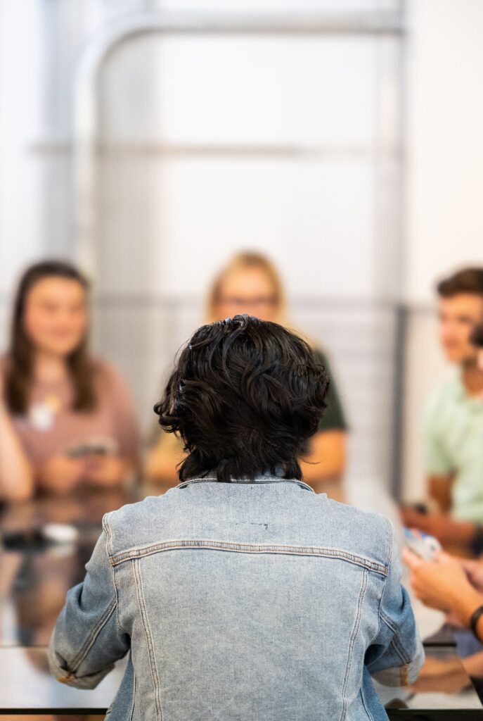 pexels photo 34516196 34516196 A group of young adults engaged in a lively discussion around a table indoors.